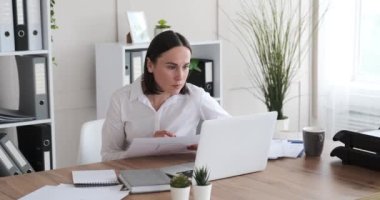 İş kadını laptopunu kullanıyor ve ofiste evrak işleriyle uğraşıyor.