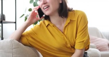 Evde cep telefonuyla konuşan bir kadın.