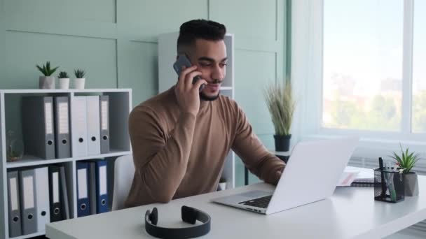 Бизнесмен с помощью мобильного телефона и ноутбука в офисе — стоковое видео