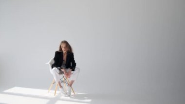 Ceketli güzel bir kadın sandalyede oturuyor.