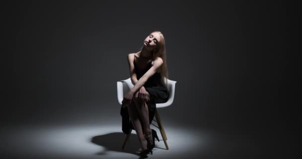 Gyönyörű divat modell ül a széken kézzel az állán — Stock videók