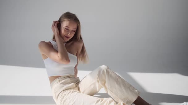 Boldog nő mosolyog és pózol, miközben a padlón ül — Stock videók
