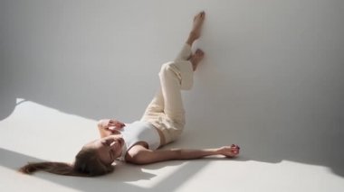 Şehvetli genç kadın ayaklarını duvara dayayıp yerde yatıyor.