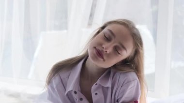 Yatakta otururken gülümseyen güzel genç kadın.