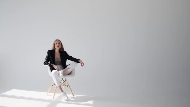 Zmysłowa młoda kobieta w marynarce siedzi na krześle — Wideo stockowe