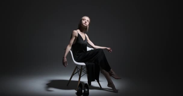 Modelo femenino sentado en silla con las piernas cruzadas — Vídeo de stock