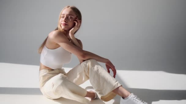 Ευτυχισμένο γυναικείο μοντέλο που ποζάρει ενώ κάθεται στο πάτωμα — Αρχείο Βίντεο