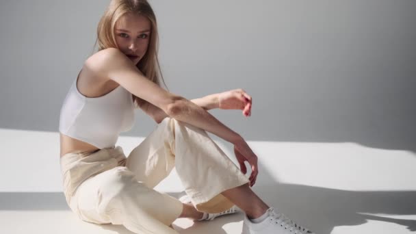 Érzéki fiatal nő pózol, miközben a padlón ül — Stock videók