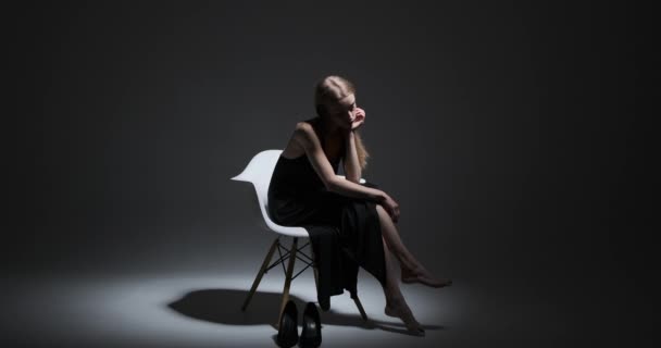 Fashion model sitting on chair with hand on chin