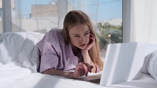 Gyönyörű fiatal nő használja laptop feküdt az ágyon — Stock videók