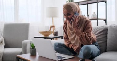 Cep telefonunda konuşurken dizüstü bilgisayar kullanan kadın