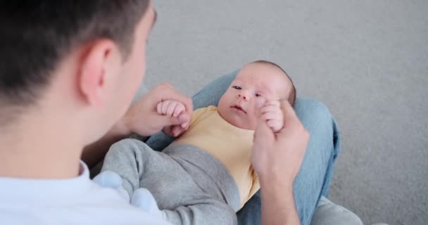 Father playing with baby son lying on lap — Stockvideo