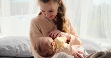 Young woman watching her baby son sleeping in arms