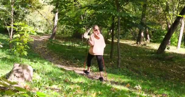 Young woman walking with hiking poles on slope — Stockvideo
