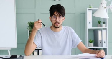 Male vlogger reading document while speaking at office