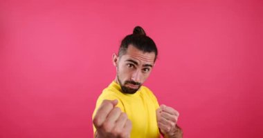 Man picking up a fight with someone over pink background