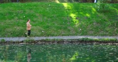 Young woman in eyeglasses running by lake in forest