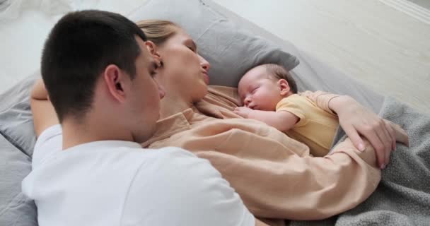 Parents with baby boy sleeping in arms while lying on bed — 图库视频影像