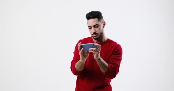 Excited young man playing game on mobile phone — Vídeos de Stock