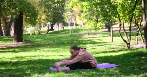 Mujer joven haciendo estiramiento y tocar los dedos de los pies ejercicio al aire libre — Vídeos de Stock