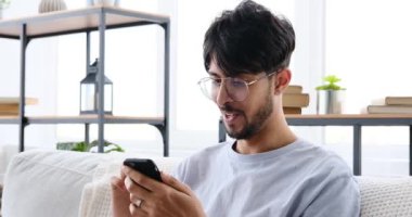 Man using mobile phone sitting on sofa at home