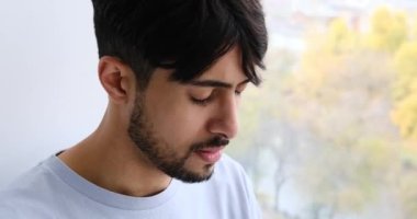 Pencereden bakan depresif bir adam.