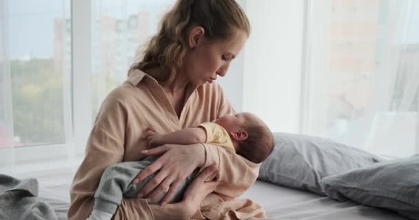 Молода жінка тримає свого маленького сина спить на руках — стокове відео