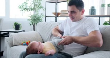 Father playing with baby son on sofa