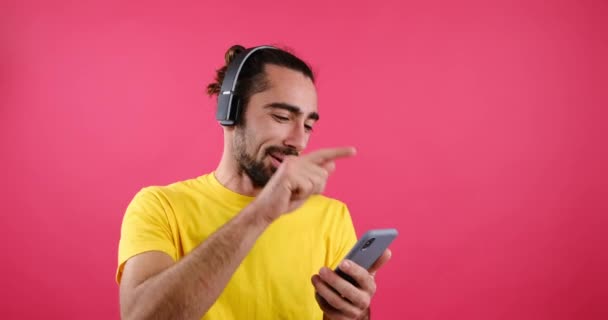 Cep telefonu ve kulaklık kullanan bir adam müzik dinliyor. — Stok video