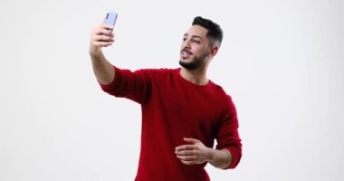 Genç adam cep telefonuyla görüntülü konuşma yapıyor.