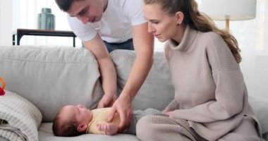 Parents playing with baby son lying on sofa