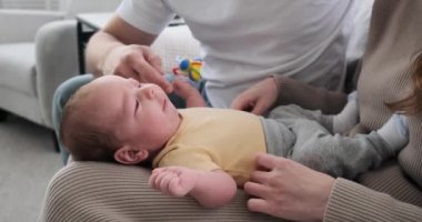 Parents playing with baby boy lying on lap