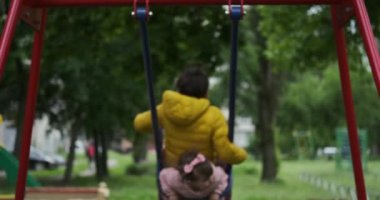 Brother and sister on enjoying on swing