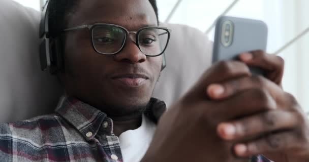Afroamerikaner benutzt Handy und hört Musik über Kopfhörer — Stockvideo