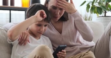 Mother and son using phone on sofa at home