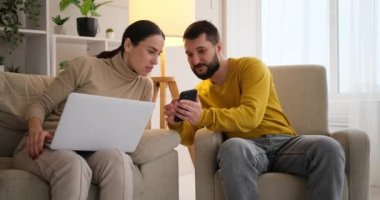 Couple using mobile phone and laptop at home
