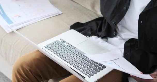 Biznesmen korzystający z laptopa i analizujący dokumenty — Wideo stockowe