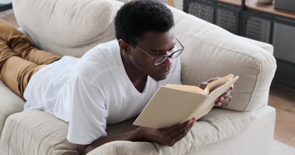 Άνθρωπος ανάγνωση βιβλίο που βρίσκεται στον καναπέ — Αρχείο Βίντεο
