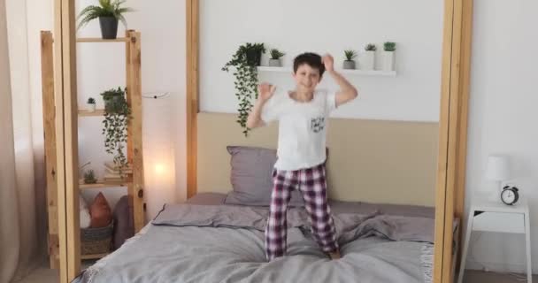 Pojke hoppar och dansar på sängen — Stockvideo