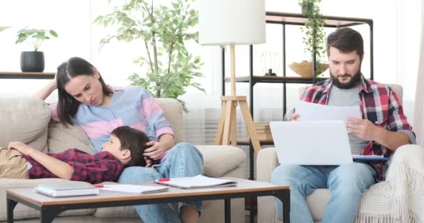Mãe com filho relaxando no sofá, enquanto o pai está trabalhando em casa — Vídeo de Stock