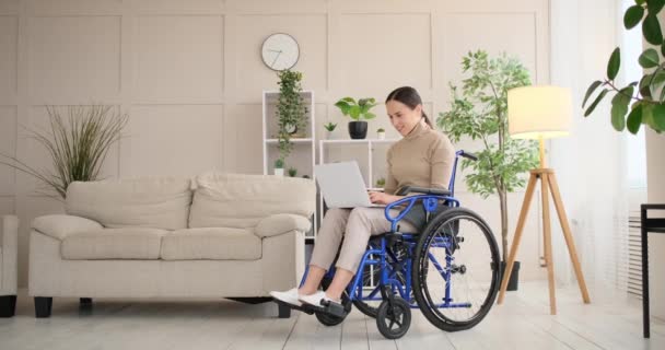 Mujer discapacitada sentada en silla de ruedas trabajando en portátil — Vídeo de stock