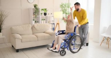 Loving husband kissing and dancing with disabled wife sitting on wheelchair at home