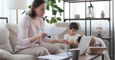 Oğlu cep telefonu kullanırken annesi evde çalışmakla meşgul.