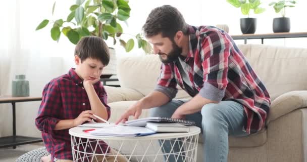 Padre ayudando a su hijo a hacer la tarea escolar — Vídeo de stock