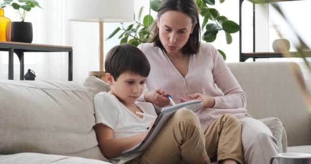 Madre ayudando a su hijo con la tarea en casa — Vídeo de stock