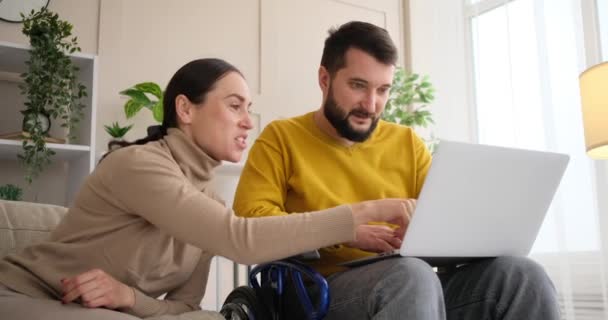 Handicapped man with wife using laptop at home — Vídeos de Stock