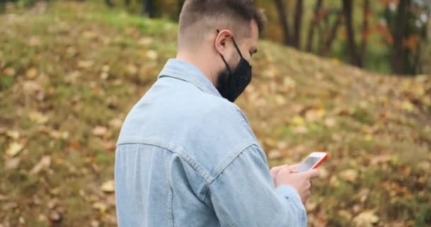 눈가리개를 하고 공원에서 휴대 전화로 문자 메시지를 보내는 남자 — 비디오