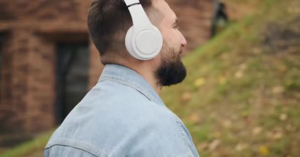 공원에서 휴대 전화와 헤드폰을 사용하여 음악을 듣는 남자 — 비디오