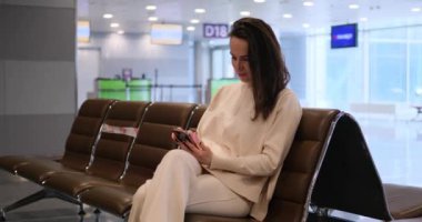 Woman messaging on mobile phone while waiting for her flight