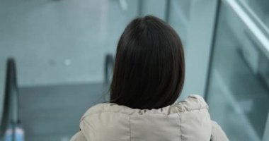 Woman standing on airport escalator